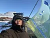 Selfie taken by a female researcher in a thick winter coat with snowy mountains in the background.