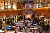 A shopping centre decorated for Christmas, and lots of people are sitting around several tables.