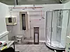 A bathroom with a shower and exposed pipes.