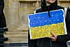 A person holds a sign with the Ukrainian flag stylised with cartoons.