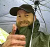 Selfie of male researcher smiling and showing a thumbs up sign with a cap on.