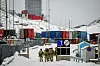 Danish soldiers walk through a snowy harbour with stacked shipping containers in Nuuk, Greenland.