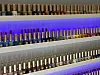 Multiple rows of colourful nail polish bottles on backlit white shelves.