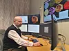 Man studies solar activity data on several monitors at an office workstation.