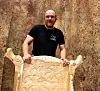 Man standing behind an ornately carved wooden high seat