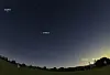 Twilight landscape with multiple planets labelled in the night sky above a dark field.