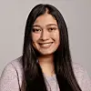 Smiling young woman with long straight hair in a studio portrait.