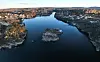 Aerial view of a calm coastal inlet with rocky islands and homes along the shore