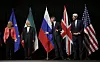 Three men and one women converse in front of five large flags