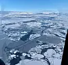Aerial view of broken sea ice with dark open water patches