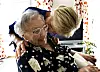 Care worker embraces an elderly woman in a bright welfare centre room