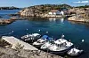 Plastic motorboats moored in a rocky cove in a Norwegian coastal landscape