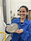 Woman in blue lab coat holding up a round filter