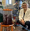Kjersti Aaby beside a lab fruit press coated with blackcurrant juice in a processing room.