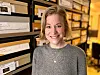 Woman standing by shelves filled with labelled archive storage boxes.