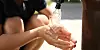 Child’s hands catching clear water from an outdoor tap
