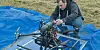 Federico Zenith adjusts a large long-range drone on a blue groundsheet outdoors.