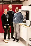 Three researchers stand beside laboratory machinery used for water research.