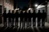 Blurred group of teenagers standing in a dark alley lit by streetlights.
