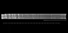 Horizontal ice core segment with layered structure above a scale on black background