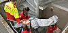 Rescue workers carry a covered patient on a stretcher down a narrow metal stairwell.