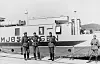 Four German soldiers stand on a pier beside the ferry Mjøsfærgen I at Gjøvik.