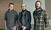 Three researchers stand indoors in front of a blank whiteboard.