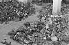Large piles of scrap metal and household metal items stacked beside a church pillar.