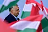 Viktor Orban in profile framed by out-of-focus Hungarian flags.