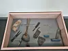 Museum case showing assorted ancient tools and stone artefacts with labels.