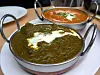 Two Indian curries in metal bowls on a white plate at a restaurant