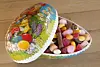 Decorative Easter bowl filled with colourful sweets on a wooden table.