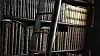 Old leather-bound books on tall shelves with a dark wooden library ladder.