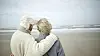 An older couple holding each other and looking out at the sea