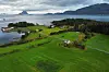 Aerial view of green peatland research fields by a fjord