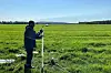 Researcher installing a water table sensor in a grassy field in western Norway.