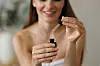 Young woman using a glass dropper to take retinol serum from a small bottle