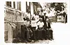 Old black-and-white photo of a group of men sat outdoors.