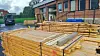 Stacks of timber test pieces outside the Wood Laboratory at NMBU, with a brick building in the background.