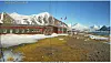 Red Arctic research station beside snowy mountains and a rocky shoreline