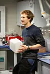 Researcher holding a white plastic container while talking in a laboratory