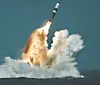 Ballistic missile rising from the ocean with fire and spray during a submarine launch.