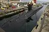 Ohio-class nuclear submarine in dock with crew working along the hull