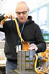 Researcher Giuseppe Guidi holding cables and testing a small SINTEF prototype in a laboratory.