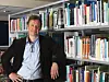 Man photographed in front of a bookshelf.