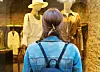 Shopper facing a boutique window display with mannequins and hanging clothes.