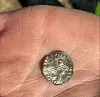 Small silver coin with cross pattern held in an open hand