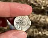 Close-up of fingers holding an old silver coin with worn markings