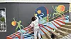 Artist in white coveralls installs a mural on an outdoor wall in Tórshavn.