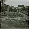 Excavated stone foundations of a medieval royal manor with city buildings behind.